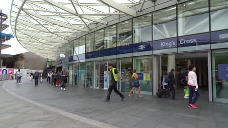 Crowd-of-people-walk-outside-Kings-Cross-Station-in-London-wearing-face-masks