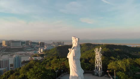 Rotating-aerial-revealing-stunning-scenery-of-Coloane,-Macau-behind-Goddess-A-Ma-statue