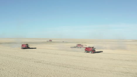 Group-of-three-Modern-Combines-slowly-harvesting-the-ripe-wheat-field-on-the-Canadian-Prairies-close-to-Swift-Current,-Saskatchewan