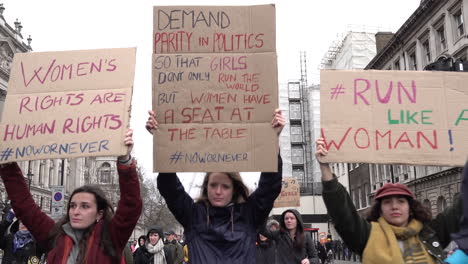 Women-walk-holding-placards-on-the-March-For-Women-in-London-on-International-Women’s-Day