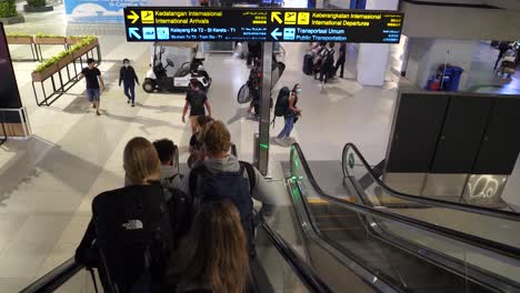 Menschen-Auf-Einer-Rolltreppe-Am-Flughafen-Tragen-Gesichtsmasken-Und-Reisen-Während-Der-Pandemie-Eines-Virus-Mit-Vorsicht-Und-Schutz