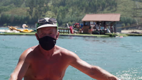 Man-Wearing-Black-Cloth-Mask-Riding-A-Motorboat-On-The-Bright-Blue-Sea-During-Summer---medium-shot