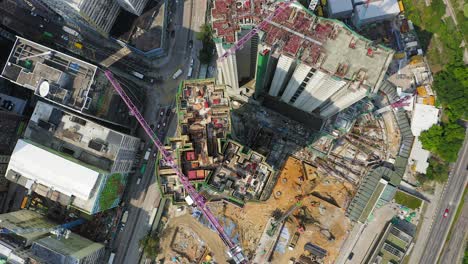 Mega-Building-Construction-site-in-downtown-Hong-Kong,-Pull-up-tilt-down-aerial-view