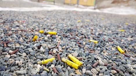Yellow-shotgun-shells-on-gravel-camera-tilts-up-to-target-backers
