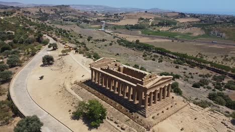 Luftaufnahme-Des-Antiken-Griechischen-Tempels-Und-Der-Wunderschönen-Hügellandschaft-Im-Hintergrund,-Sizilien,-Italien