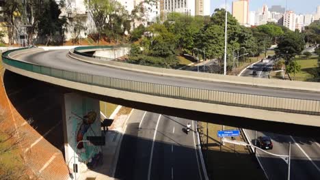 high-view-of-a-viaduct-over-a-large-avenue-with-vehicle-traffic,-and-cityscape-around