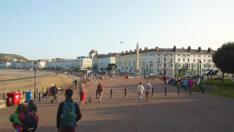 Slow-mo-of-tourists-walking-along-Llandudno-promenade,-Wales