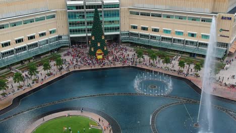 Establecimiento-De-Una-Vista-Aérea-Del-Centro-Comercial-Klcc-Desde-Atrás-Con-Un-Parque-Y-Fuentes-Durante-La-Navidad-Con-Un-árbol-De-Navidad-En-Kuala-Lumpur,-Malasia