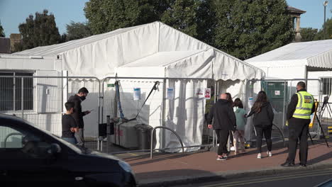 A-family-is-directed-into-the-entrance-of-an-appointment-only-Covid-19-testing-centre-by-Serco-security-staff-as-others-queue-up-outside-wearing-protective-face-masks