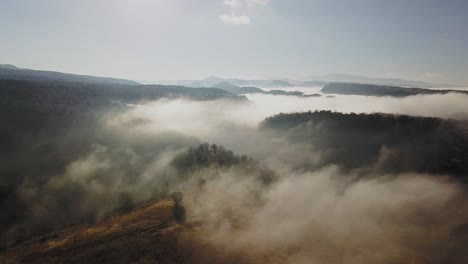 Aerial-view-of-vast-land-in-golden-color-enveloped-in-fog,-zooming-out-shot