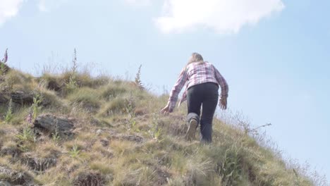 Woman-climbing-hill-in-rugged-moorland-medium-landscape-shot