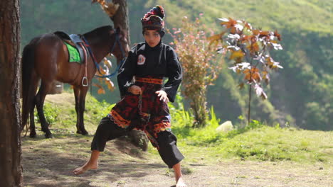 Eine-Junge-Frau,-Die-Auf-Einem-Hügel-Mit-Pferdehintergrund-Kampfkunst-Praktiziert