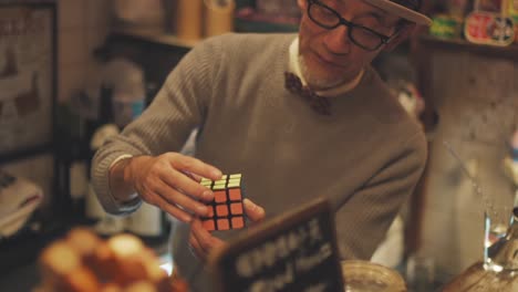 Un-Hombre-De-Mediana-Edad-Resolviendo-Un-Cubo-De-Rubik-En-Tokio,-Japón---Tiro-De-Pedestal-Hacia-Arriba