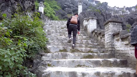 Subiendo-Los-Escalones-De-Piedra-De-Hang-Mua-Hasta-La-Pagoda-Con-Otras-Personas-Tomando-Descansos-Para-Mirar,-Toma-De-Mano