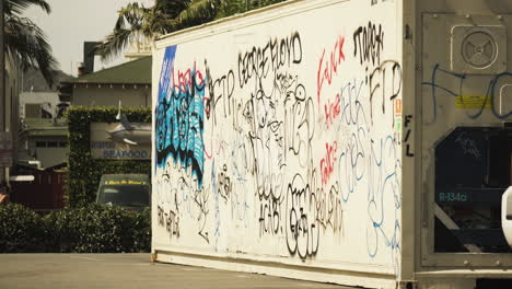 BLM-Graffiti-Auf-Einem-Container-In-Los-Angeles,-An-Dem-Demonstranten-Vorbeigehen