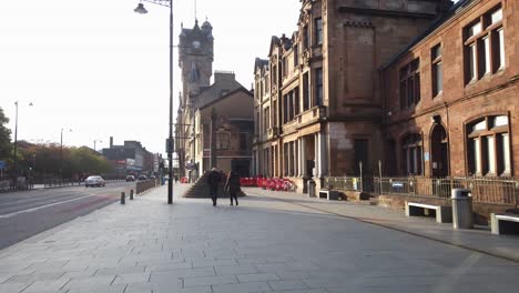 A-man-and-woman-walk-up-a-quiet-British-main-street