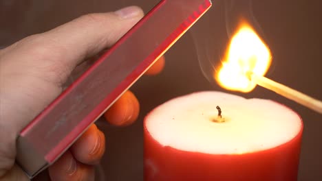 Male-hand-lighting-match-and-igniting-candle