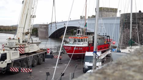 Hydraulic-crane-vehicle-lifting-fishing-boat-on-Conwy-Wales-harbour