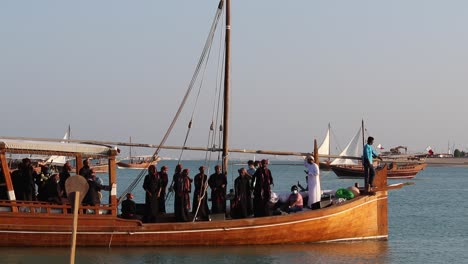 Ein-Blick-Auf-Ein-Traditionelles-Holzboot,-Bekannt-Als-Dhau,-Das-Eine-Gruppe-Einheimischer-Trägt,-Die-Anlässlich-Des-Dhau-Festivals-Im-Dorf-Katara,-Doha,-Katar,-Singen-Und-Tanzen