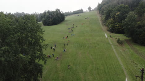Aerial-Shot-Of-People-Standing-On-A-Mountain-Watching-Downhill-Grass-Ski-Competition-Sport
