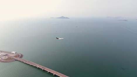 Commercial-airplane-approaching-Hong-Kong-International-airport,-passing-above-Hong-Kong-Zhuhai-Macao-Bridge,-the-longest-Sea-crossing-in-the-world