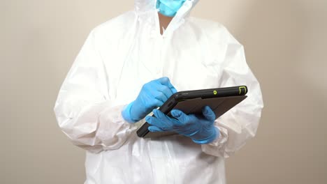 female-doctor-dressed-in-ppe-suit-using-tablet-to-consult-information-during-the-service