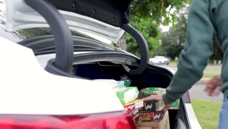 Packs-Of-Food-In-The-Car-Trunk-For-Donating-To-The-Homeless-During-Covid-19-Pandemic---side-view,-slow-motion