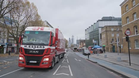 Cars-driving-down-London-Whitechapel-road-with-city-centre-in-background-wide