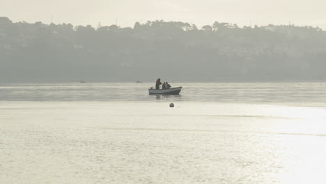 Fishermen-On-A-Boat-At-Calm-Lake-In-Obidos-Lagoon-Near-Foz-do-Arelho-Beach-In-Portugal-During-Hazy-Morning