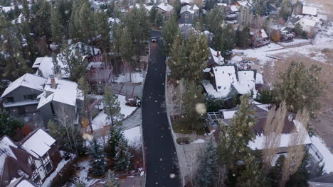 Car-Driving-Through-Small-Picturesque-Snowy-Neighborhood-at-Winter-Time,-Aerial-Shot