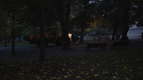 Bulldozer-drives-through-a-park-in-the-early-morning-during-blue-hour