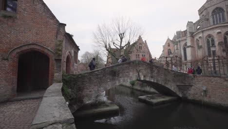 La-Gente-Cruza-En-El-Puente-Bonifacius-Cerca-De-La-Iglesia-De-Nuestra-Señora-En-Brujas,-Bélgica-Durante-La-Pandemia