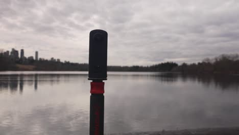 360-Grad-Kamera-Auf-Einem-Einbeinstativ-Am-Rande-Eines-Sees,-Die-Landschaftsfotografie-Und-Videografie-Von-Wasser,-Wolken,-Bäumen-Und-Himmel-Aufnimmt