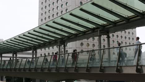People-walk-through-a-pedestrian-bridge-in-Central,-the-financial-district-of-Hong-Kong