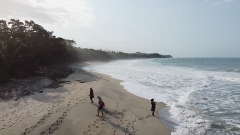 Low-aerial-slowly-rises-over-tourist-heads-on-uncrowded-misty-beach