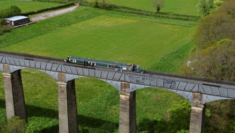 Vista-Aérea-Siguiendo-Barco-Estrecho-En-La-Cuenca-De-Trevor-Cruce-Del-Acueducto-Pontcysyllte-En-El-Campo-Del-Valle-Galés-Seguimiento-Creciente-Izquierda