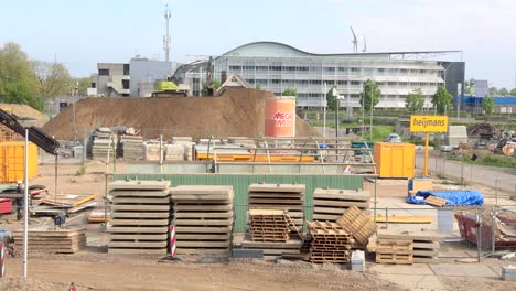 Derribar-El-Cobertizo-Del-Taller-De-Hierro-Corrugado-En-El-Sitio-De-Construcción-Y-Transportarlo-A-Otro-Lugar-Con-En-El-Fondo-Una-Excavadora-Y-Molinos-De-Viento