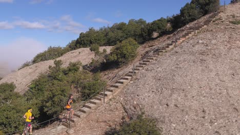 Gente-Subiendo-Escaleras-Por-Una-Montaña-Mediterránea,-Seguimiento-Aéreo