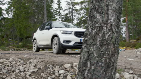 Volvo-XC40-SUV-car-crossover-on-Forest-Dirt-Road-Behind-Tree,-Handheld