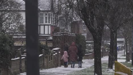 Mother-Walking-With-Children-On-Pavement-Whilst-Its-Snowing