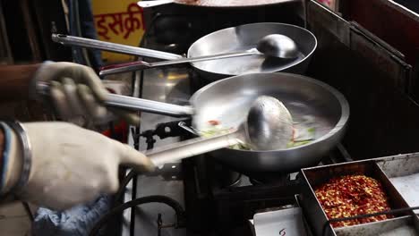 Professional-chef-fries-vegetables-to-prepare-white-sauce-Pasta-at-a-street-food-shop-at-Chat-Gali-in-Agra,-India-on-07-March-2021