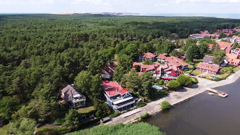 Beautiful-town-of-Pervalka-surrounded-by-dense-pine-forest-on-sunny-day,-aerial-drone-view