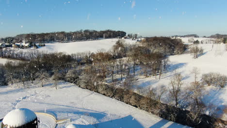 AERIAL-Snow-Falling-Over-Rural-Farmland-And-Silo-Towers