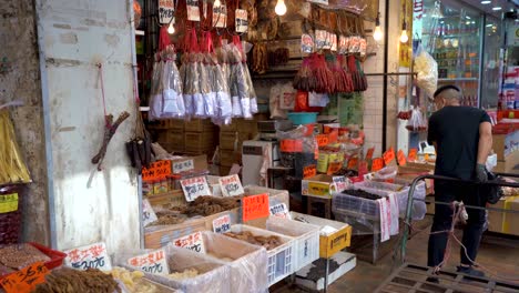 People-Walking-By-Dry-Food-Stall-At-Des-Voeux-Road-West,-Sai-Ying-Pun,-Hong-Kong