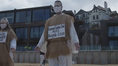 Los-Manifestantes-Se-Paran-En-La-Playa-Protestando-Contra-El-Hotel-Carbis-Bay,-Cornwall-Por-Daños-Ambientales
