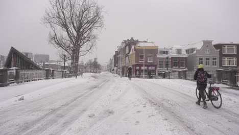 Dutch-locals-cycling-on-snowy-Leiden-city-roads,-Netherlands-winter