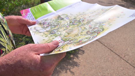 Manos-De-Un-Anciano-Sosteniendo-Y-Mirando-El-Mapa-Del-Museo-Del-Desierto-De-Arizona-sonora-En-Tucson,-Arizona,-Ee.uu.