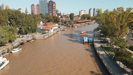 Barco-Navegando-En-El-Agua-Marrón-Del-Río-En-Un-Día-Soleado-Cerca-De-La-Estación-Del-Río-Tigre-En-Tigre,-Buenos-Aires,-Argentina