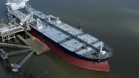 Crude-oil-tanker-ship-loading-at-refinery-harbour-terminal-aerial-view-over-deck-orbit-right