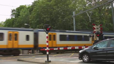 Autos-Und-Menschen,-Die-Im-Sommer-In-Einer-Niederländischen-Stadt-An-Einem-Bahnübergang-Auf-Die-Durchfahrt-Des-Zuges-Warten